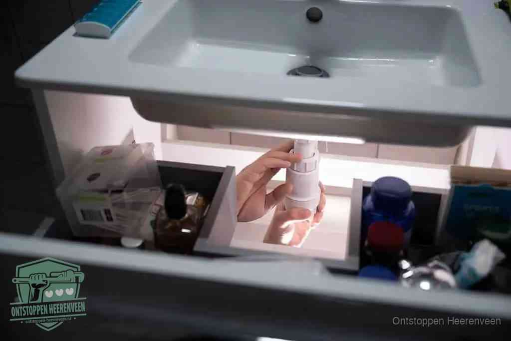 Een pompfles met zeep boven een wastafel, de heet water en afwasmiddel-methode om een vetprop in de afvoer los te maken in Heerenveen