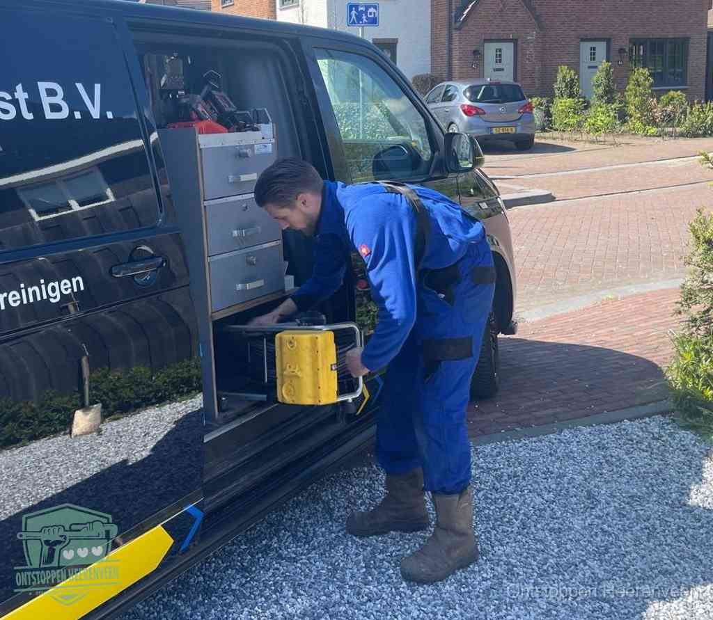 Een monteur pakt buiten op de oprit gereedschap uit de bedrijfsbus, het moment om een professional in te schakelen voor een verstopte afvoer in Heerenveen