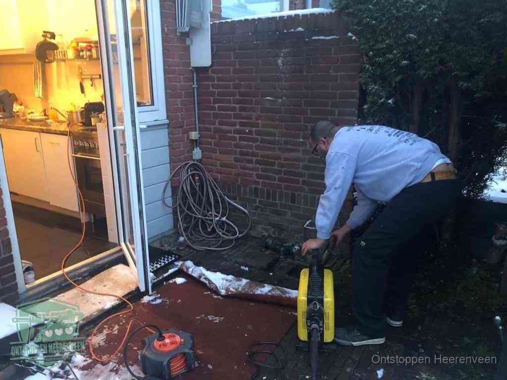 Een monteur werkt buiten bij een open riool-/grondput met een elektrische ontstoppingsmachine om een verborgen afvoerprobleem op te sporen in Heerenveen