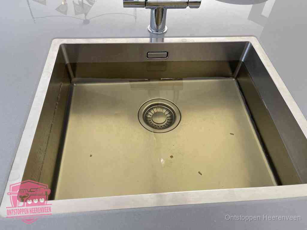 Stilstaand water in een rvs spoelbak dat niet wegloopt, een duidelijk signaal van een gootsteenverstopping in Heerenveen