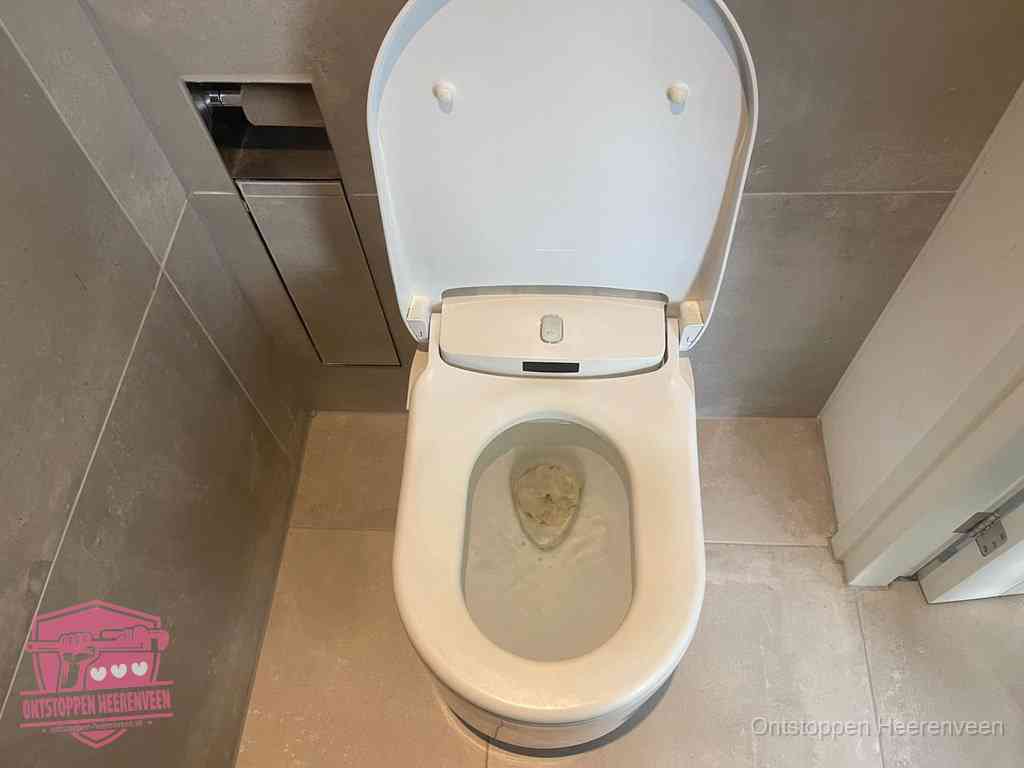 Een wit hangtoilet waarin een prop wc-papier op het water blijft drijven, een duidelijk signaal van een verstopte wc in Heerenveen