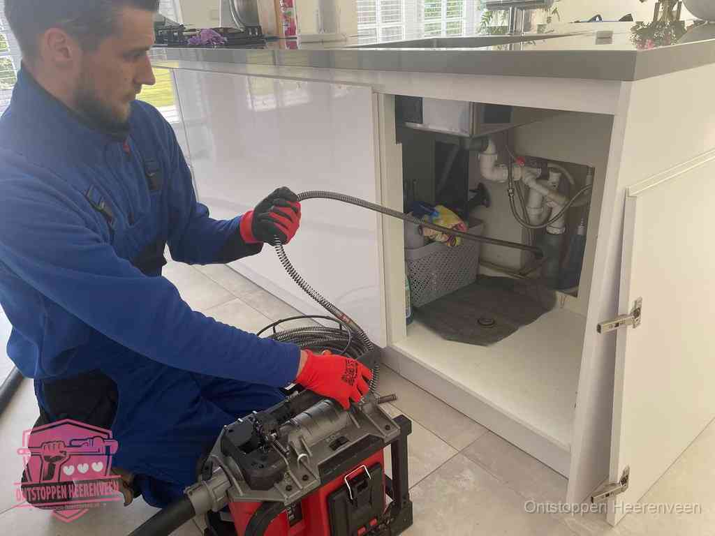 Een monteur reinigt de keukenafvoer grondig met een veermachine om terugkerende gootsteenverstoppingen te voorkomen in Heerenveen