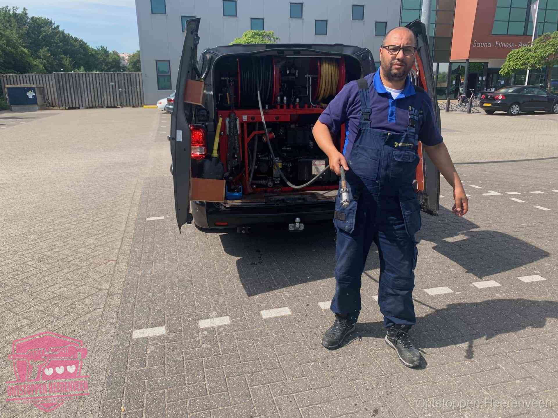 Een monteur bij zijn bestelbus met een hogedruk- en rioolreinigingsunit, klaar om de oorzaak van terugkerende wc-verstoppingen aan te pakken in Heerenveen