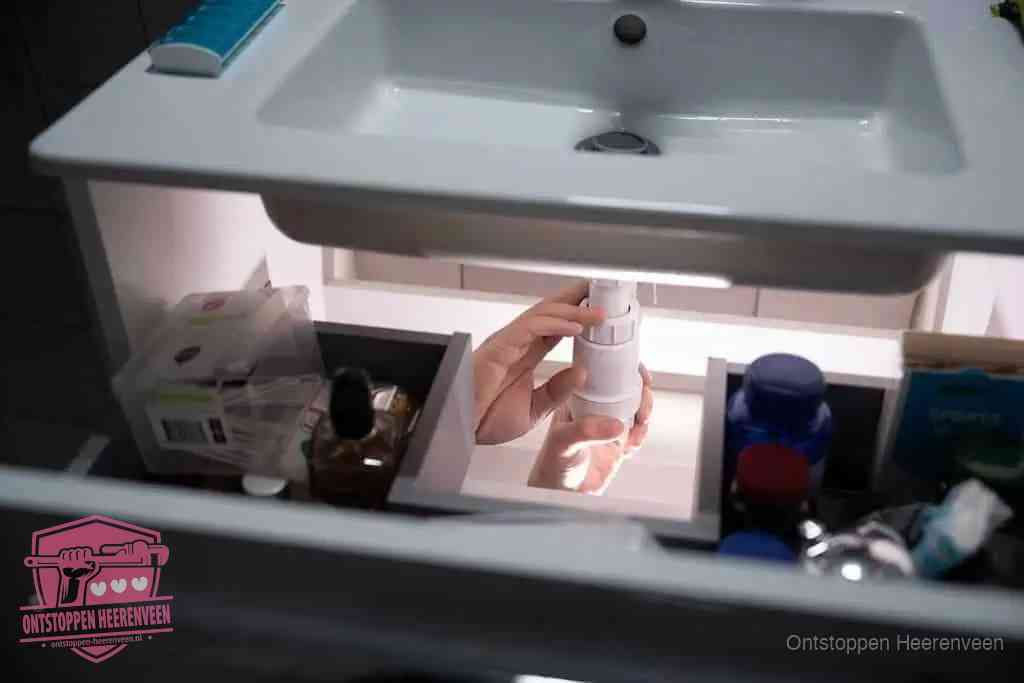 Een pompfles met zeep boven een wastafel in de toiletruimte, de warm water en afwasmiddel-methode om de wc te ontstoppen in Heerenveen