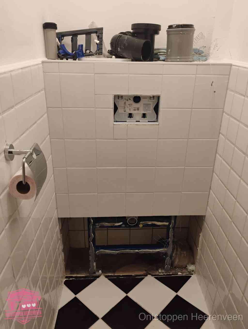 Een toiletruimte waar het hangtoilet en de inbouwreservoir-onderdelen zijn vrijgelegd voor onderhoud, periodiek nazicht voorkomt een wc-verstopping in Heerenveen