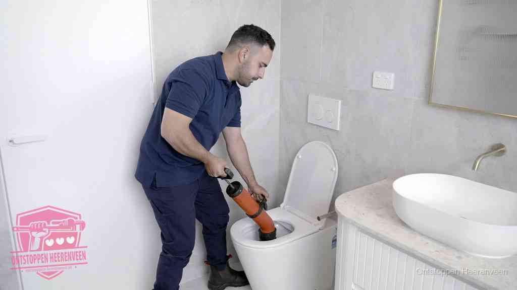 Een monteur gebruikt een handmatige perspomp (toiletontstopper) op een wandcloset tijdens het professioneel wc ontstoppen in Heerenveen